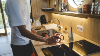 Man making coffee in modern kitchen at Wrap house with sauna and bathtub at Resort de Parel, Netherlands.