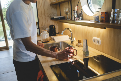 Uomo prepara il caffè in cucina moderna al Wrap house con sauna e vasca da bagno presso Resort de Parel, Paesi Bassi.