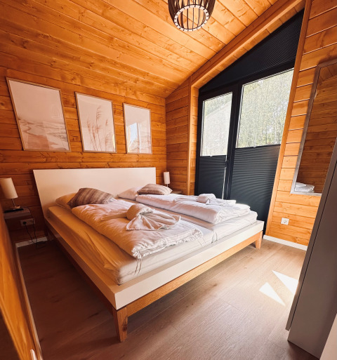 Dormitorio en Lakehouse Scandi en Wilsumer Berge, Alemania, con paredes de madera y decoración moderna.