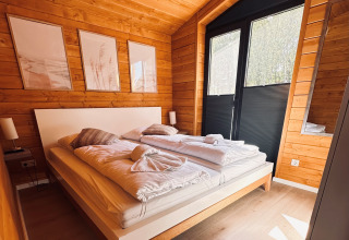 Soveværelse i Lakehouse Scandi ved Wilsumer Berge, Tyskland, med trævægge og moderne indretning.