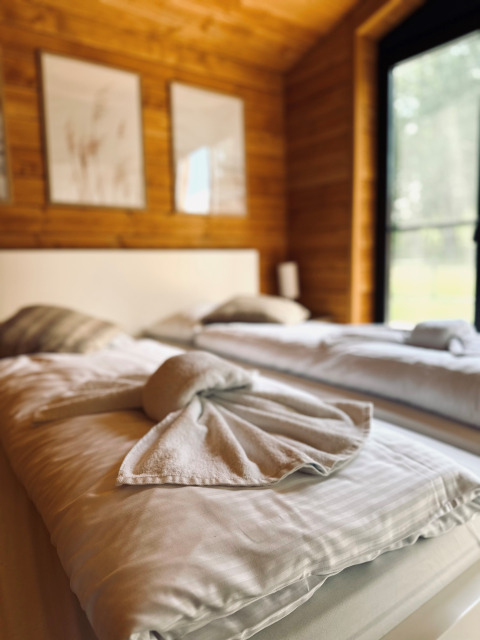 Dormitorio acogedor en Lakehouse Scandi, Wilsumer Berge, Alemania, con arte de toalla doblada en la cama.