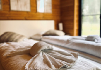 Knusse slaapkamer in Lakehouse Scandi, Wilsumer Berge, Duitsland, met sierlijk gevouwen handdoeken op het bed.