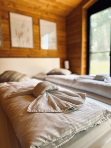 Gemütliches Schlafzimmer im Lakehouse Scandi, Wilsumer Berge, Deutschland, mit kunstvoll gefalteten Handtüchern.