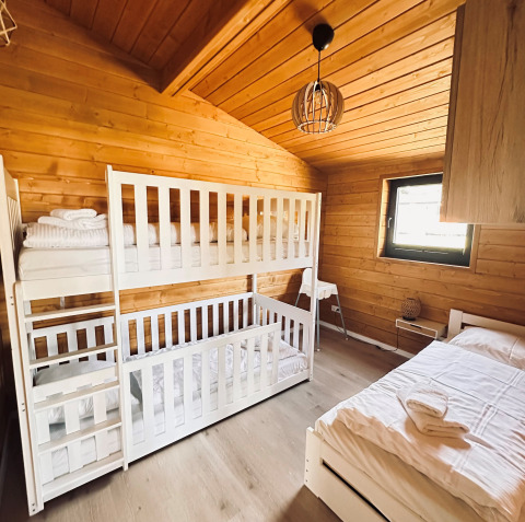 Acogedor dormitorio de madera con literas y cama individual en Lakehouse Scandi, Wilsumer Berge, Alemania.