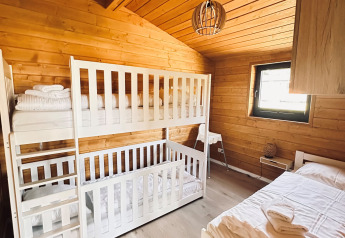 Knusse houten slaapkamer met stapelbedden en eenpersoonsbed in Lakehouse Scandi, Wilsumer Berge, Duitsland.