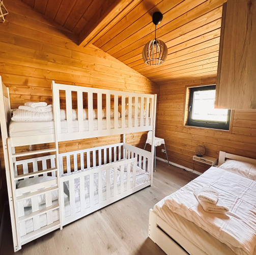 Gemütliches Schlafzimmer mit Etagenbetten und Einzelbett im Lakehouse Scandi, Wilsumer Berge, Deutschland.