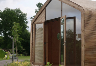 Vista exterior de la Wrap house con sauna y bañera en el Resort de Parel, Países Bajos, rodeada de verde.