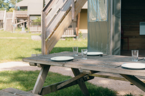 Mesa de picnic al aire libre con platos y vasos en Safaricottage XS, Holiday Park Sallandshoeve, Países Bajos.