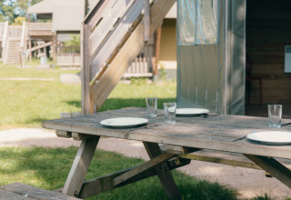 Mesa de picnic al aire libre con platos y vasos en Safaricottage XS, Holiday Park Sallandshoeve, Países Bajos.