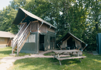 Tente safari à deux étages avec terrasse et petite tente annexe au Holiday Park Sallandshoeve, entouré d'arbres.