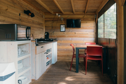 Interior de cocina compacta y comedor en Safaricottage XS con baño en Holiday Park Sallandshoeve, Países Bajos.