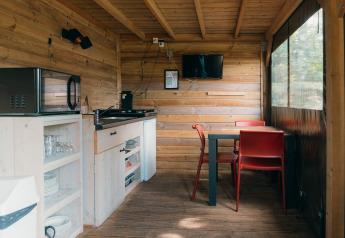 Interior de cocina compacta y comedor en Safaricottage XS con baño en Holiday Park Sallandshoeve, Países Bajos.