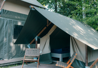 Tente safari Safaricottage XS avec terrasse et deux chaises au Holiday Park Sallandshoeve aux Pays-Bas, arbres autour.