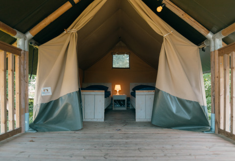 Interior of Safaricottage XS tent with two single beds and lamp at Holiday Park Sallandshoeve, Netherlands.