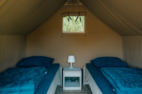 Interior de Safaricottage XS con dos camas individuales y mesita en Holiday Park Sallandshoeve, Países Bajos.