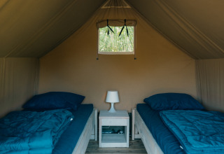 Interior de Safaricottage XS con dos camas individuales y mesita en Holiday Park Sallandshoeve, Países Bajos.
