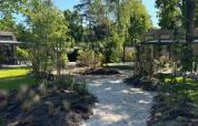 Zonnig zandpad in groene tuin bij Reeëndal Lodge, Veluwepark de Bosgraaf, Nederland.