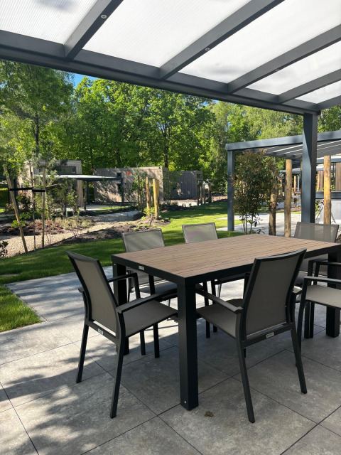 Outdoor dining area under a covered patio at Reeëndal Lodge, Veluwepark de Bosgraaf, Netherlands.