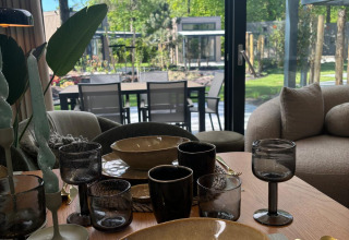 Set dining table at Reeëndal Lodge, Veluwepark de Bosgraaf, Netherlands, with view to patio and garden.