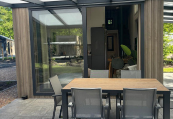 Outdoor dining area at Reeëndal Lodge, Veluwepark de Bosgraaf in the Netherlands, with modern furniture.