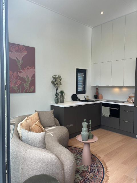 Moderner Wohnbereich und Küche mit gebogener Couch und Kunstwerk in der Reeëndal Lodge, Veluwepark de Bosgraaf.