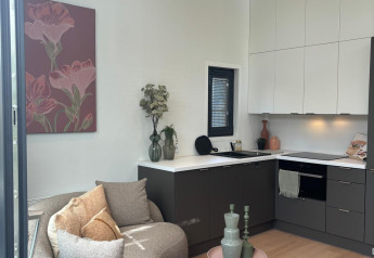 Modern lodge living area and kitchen with curved sofa, floral art, and light wood at Reeëndal Lodge, Veluwepark de Bosgraaf.