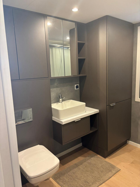 Modernes Badezimmer in Reeëndal Lodge, Veluwepark de Bosgraaf, Niederlande, mit grauen Schränken.
