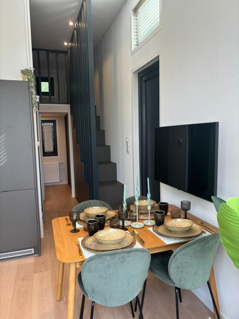 Moderner Essbereich mit vier grünen Stühlen, Holztisch und Fernseher in der Reeëndal Lodge, Veluwepark.
