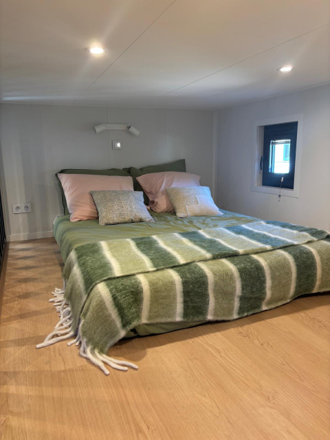Gemütliches Schlafzimmer im Reeëndal Lodge im Veluwepark de Bosgraaf, Niederlande, mit einem niedrigen Dach und Deko in Grün.