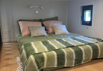 Cozy bedroom at Reeëndal Lodge in Veluwepark de Bosgraaf, Netherlands, featuring a low ceiling and soft green decor.
