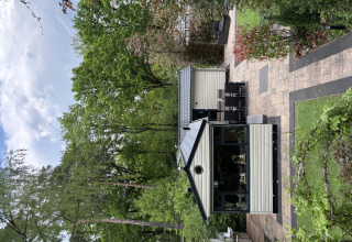 Et hyggeligt Veluwe Chalet i Veluwepark de Bosgraaf, Holland, omgivet af frodige træer og have.