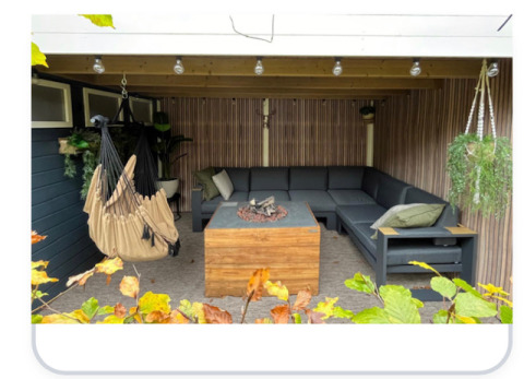 Gemütliche überdachte Terrasse mit Lounge-Sofa, Hängesessel und Feuerstelle im Veluwe Chalet, Niederlande.