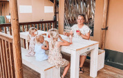 Familia sentada en mesa frente a tienda Ranger Lodge en Holiday Park Sallandshoeve, Países Bajos.