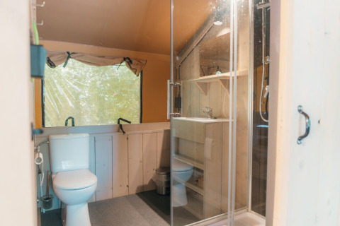 Baño con inodoro, lavabo y ducha en una tienda safari de Ranger Lodge, Holiday Park Sallandshoeve, Países Bajos.