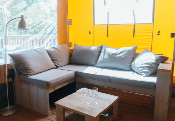 Bright lounge inside a Ranger Lodge safari tent at Holiday Park Sallandshoeve, Netherlands, with sofa and table.