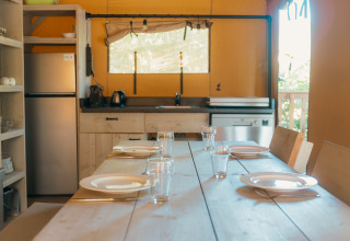 Cucina luminosa nella tenda safari Ranger Lodge presso Holiday Park Sallandshoeve, tavola apparecchiata.