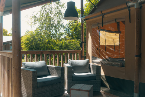 Véranda confortable de la tente safari Ranger Lodge au Holiday Park Sallandshoeve, Pays-Bas, avec fauteuils.