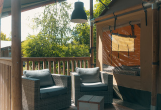 Véranda confortable de la tente safari Ranger Lodge au Holiday Park Sallandshoeve, Pays-Bas, avec fauteuils.
