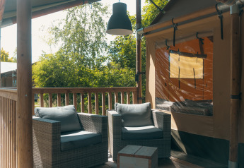 Véranda confortable de la tente safari Ranger Lodge au Holiday Park Sallandshoeve, Pays-Bas, avec fauteuils.