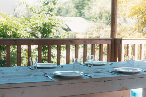 Outdoor wooden table set for four with plates, glasses, and cutlery at Ranger Lodge, Sallandshoeve, Netherlands.