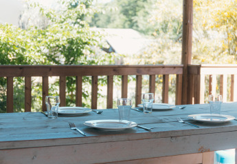 Outdoor wooden table set for four with plates, glasses, and cutlery at Ranger Lodge, Sallandshoeve, Netherlands.