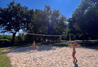 Zwei Menschen spielen Beachvolleyball bei strahlendem Sonnenschein im Camping Le Périgord, Nouvelle-Aquitaine.