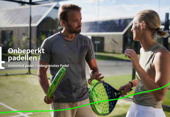 To personer spiller padel på Unbrick One Lodge i Brinckerduyn, Holland, med rackets og bold under solen.
