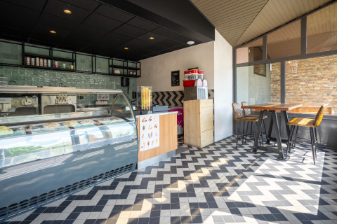 Gelateria moderna e luminosa in un glamping, con pavimento a motivi e area tavoli accogliente.