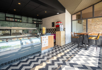 Bright, modern ice cream shop at glamping site with stylish décor, patterned floor, and seating area.