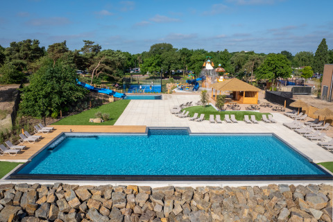 Outdoor swimming pool with lounge chairs, slides, and water playground at a glamping accommodation site.