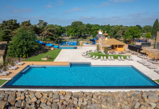 Outdoor swimming pool with lounge chairs, slides, and water playground at a glamping accommodation site.