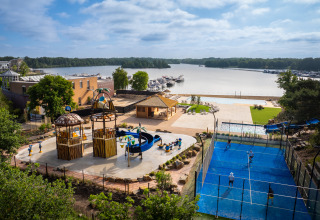 Modern glamping site featuring a playground, padel court, pool and scenic lake views with boats.