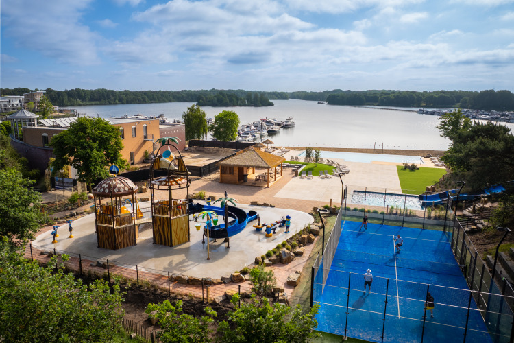 Moderne glamping met speeltuin, padelbaan, zwembad en uitzicht op het meer en de jachthaven.