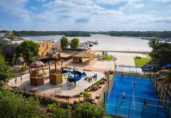 Moderne glampingplads med legeplads, padelbane, swimmingpool og udsigt over søen og bådehavnen.